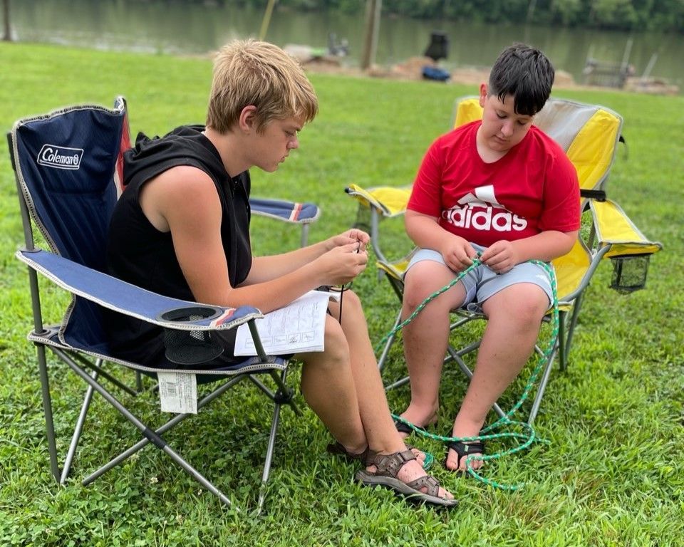 Two people sitting in lawn chairs on grass, focused on a green object between them.