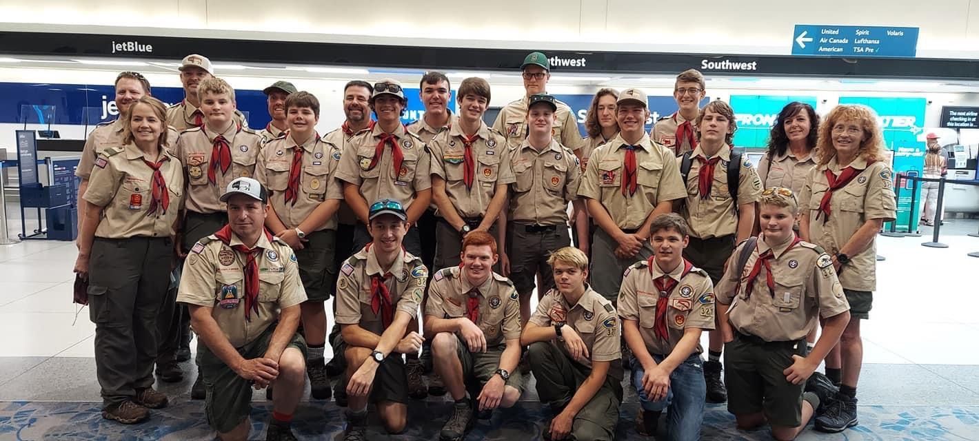 Scout group in tan uniforms posing together indoors at an airport