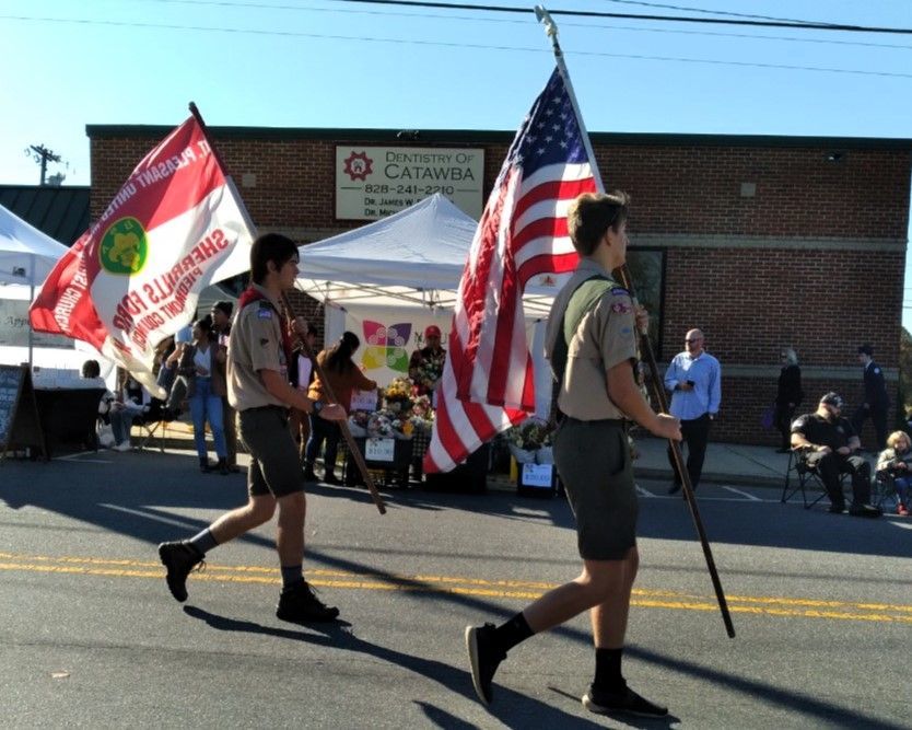 Two scouts marching in a parade with American and California state flags