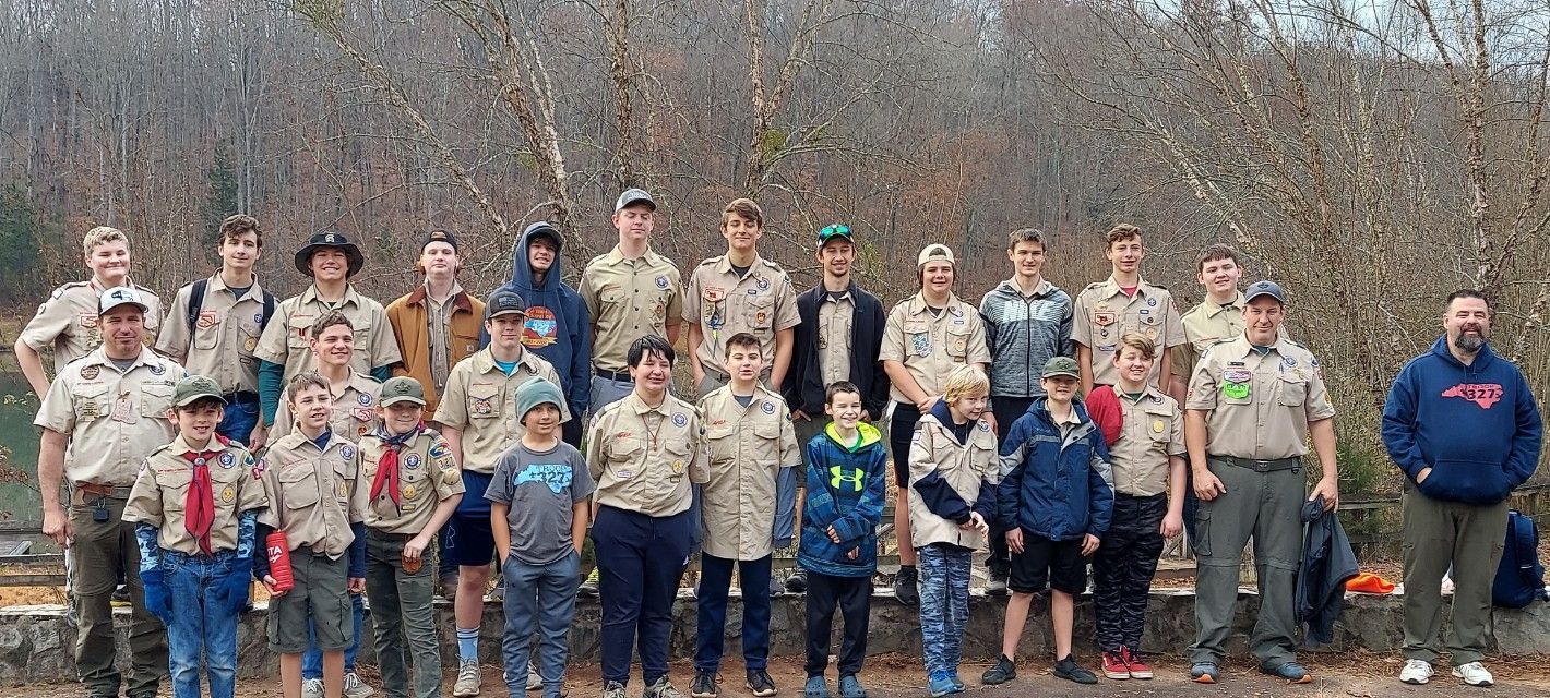 Group of people and children posing outdoors in camouflage shirts in a wooded area