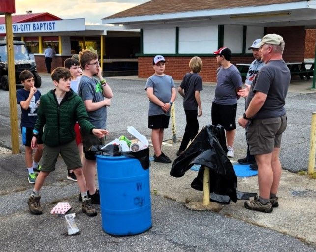 Volunteers gathered outside a church, standing near blue barrels and a pile of bagged items.