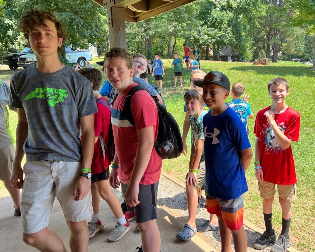 A group of young boys are standing under a pavilion in a park.