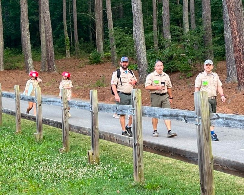 A group of boy scouts are walking down a path in the woods