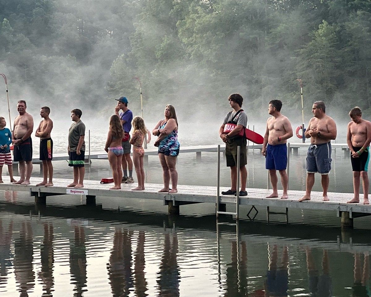 A group of people standing on a dock overlooking a body of water