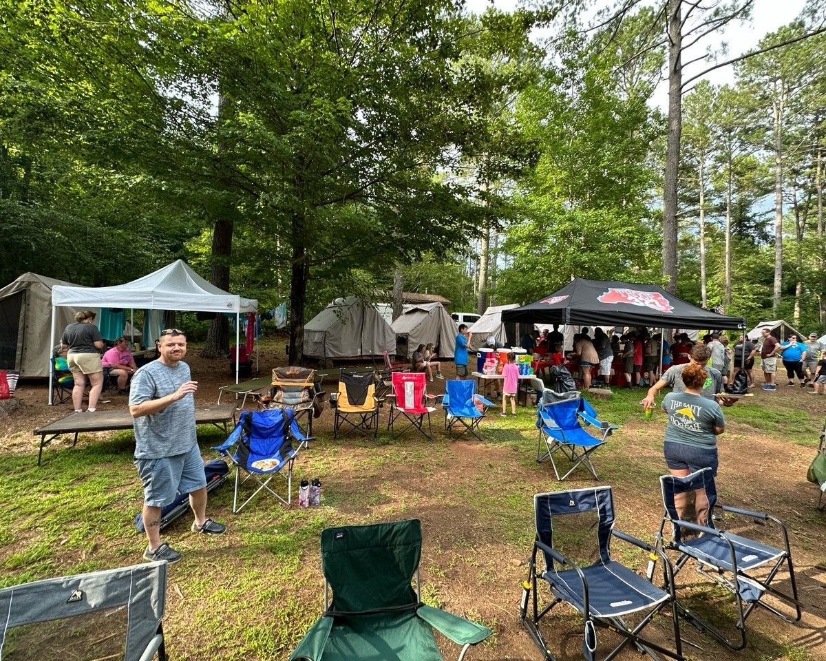A group of people are standing in a field with chairs and tents.