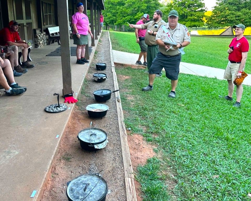 A group of people are standing around a row of pots and pans.