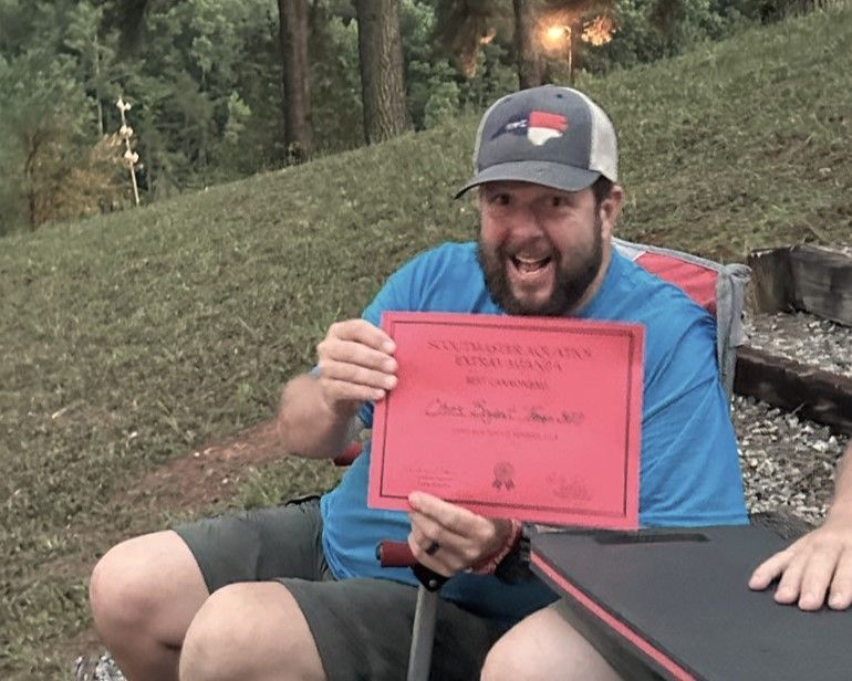 A man in a blue shirt is holding a red certificate