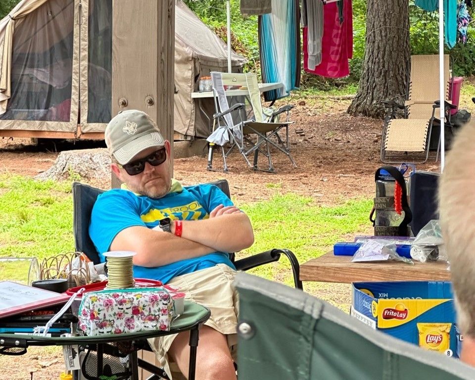 A man is sleeping in a chair at a campground.