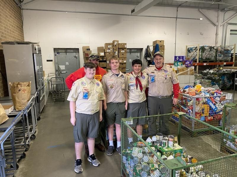 A group of boy scouts are posing for a picture in a warehouse.