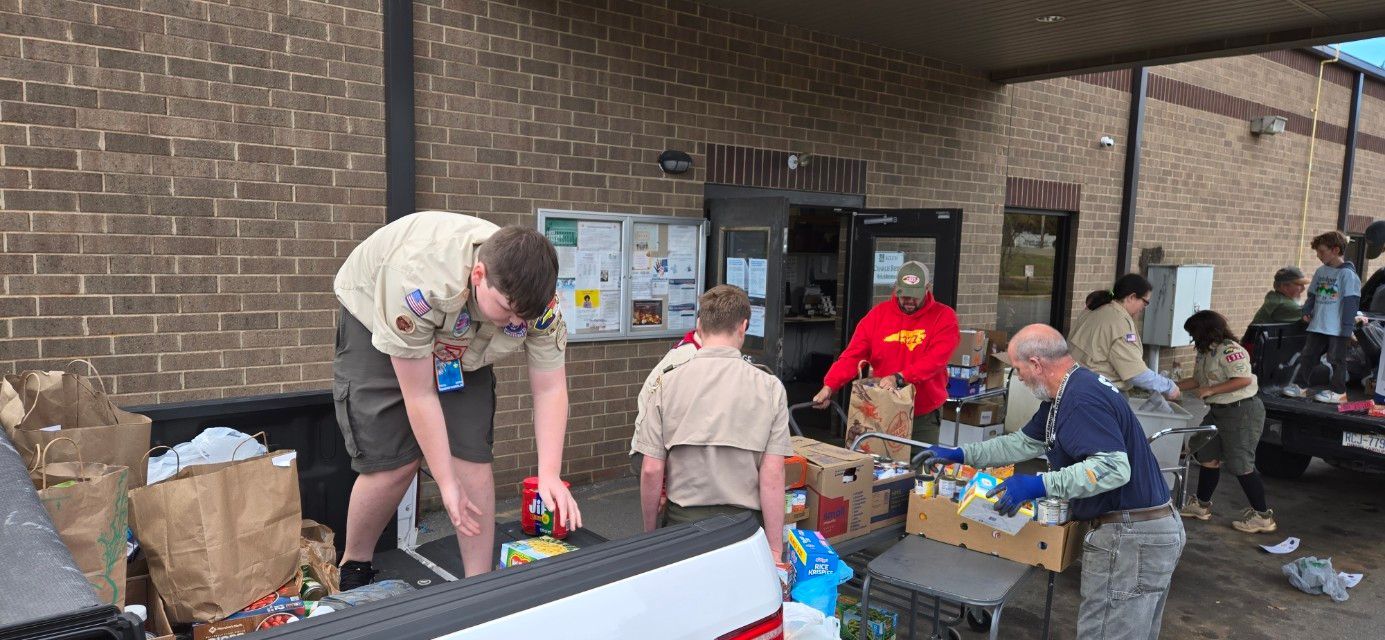 A group of boy scouts are loading food into a truck.