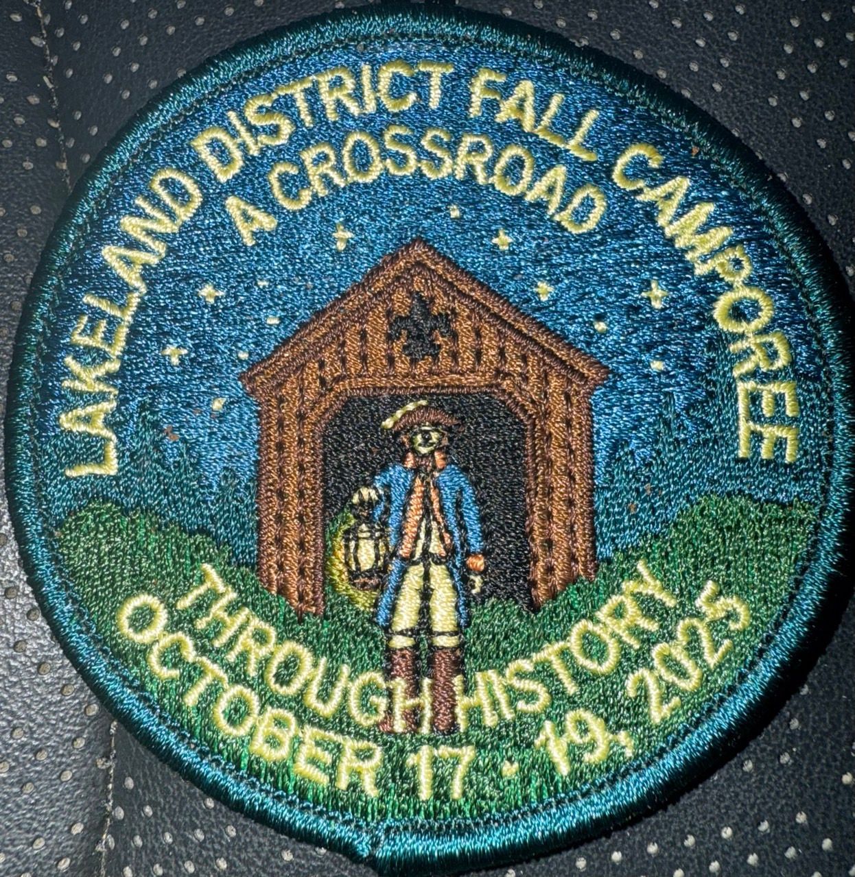 Lakewood District Fall Camporee patch with a tent, hiker, and blue-green background; “A Crossroads Through History”[0m