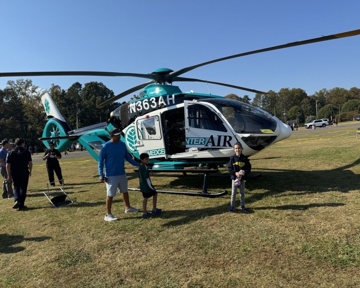 A group of people standing in front of a helicopter that says n363ah