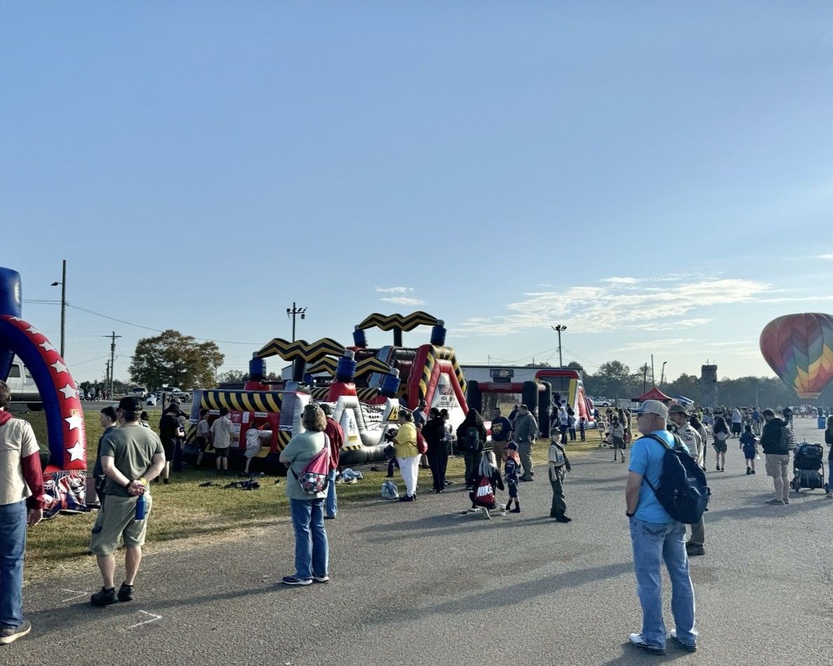 A group of people are standing in front of a hot air balloon.