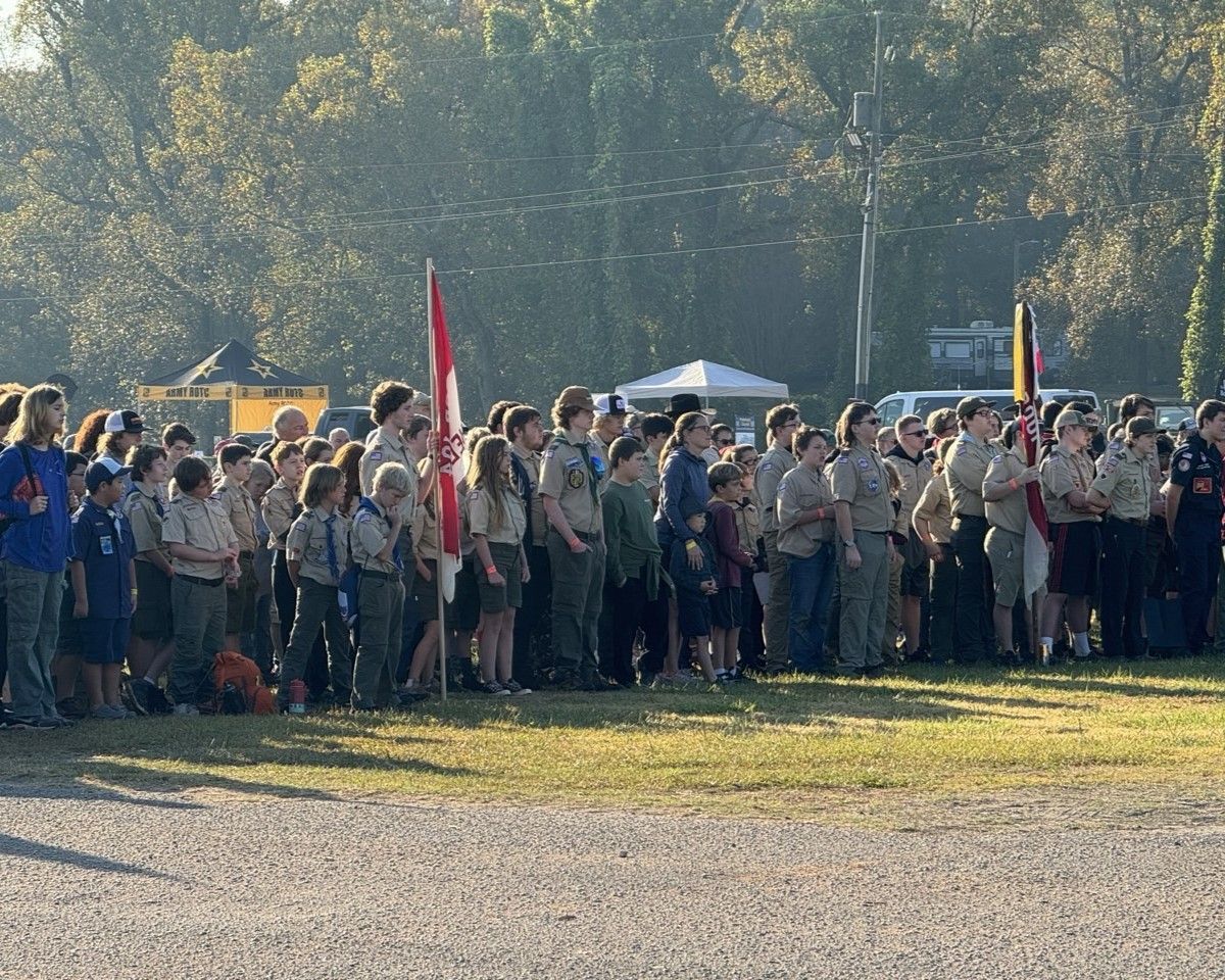 A large group of boy scouts are standing in a field