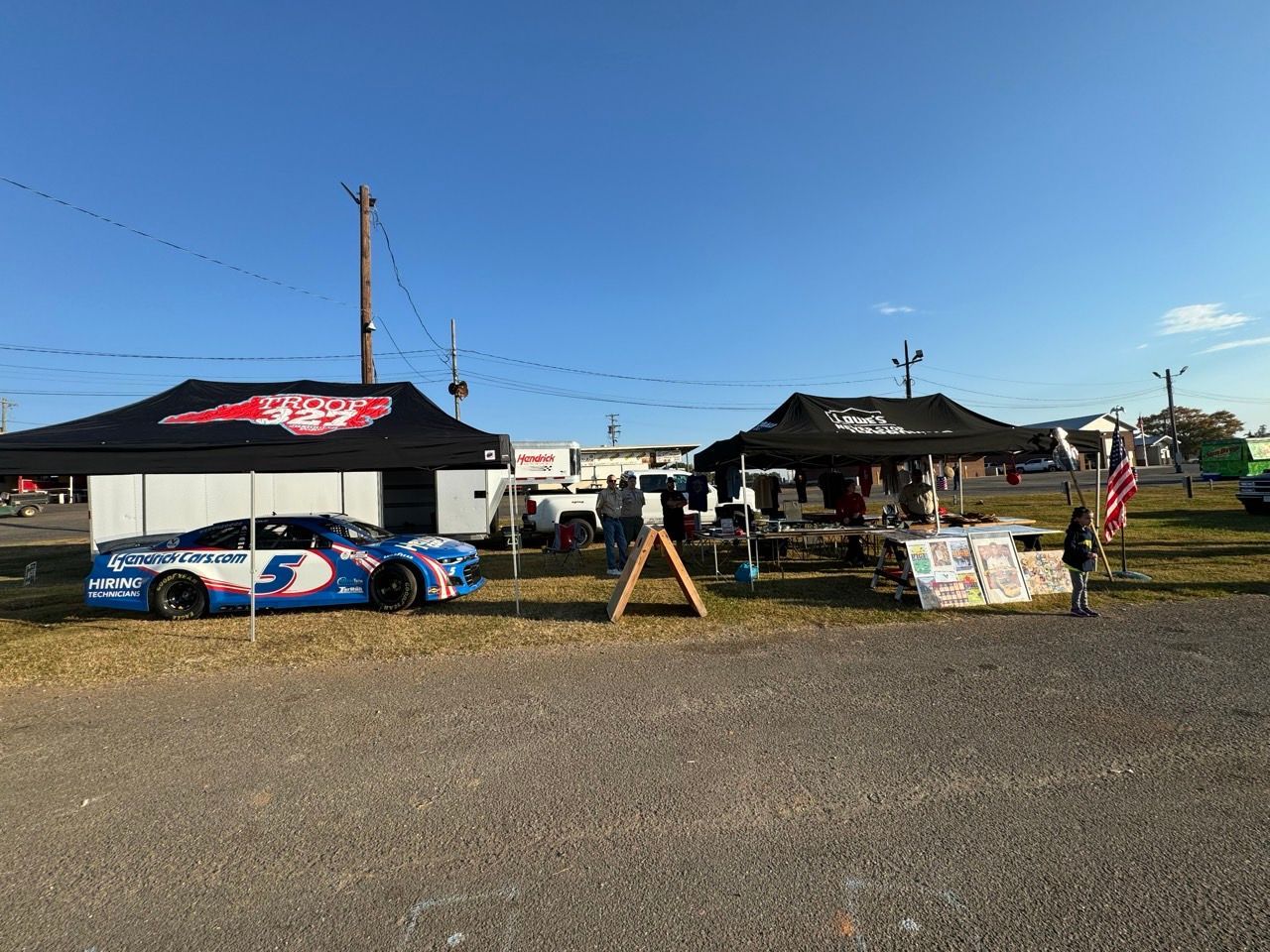 A race car is parked in a parking lot next to a tent.