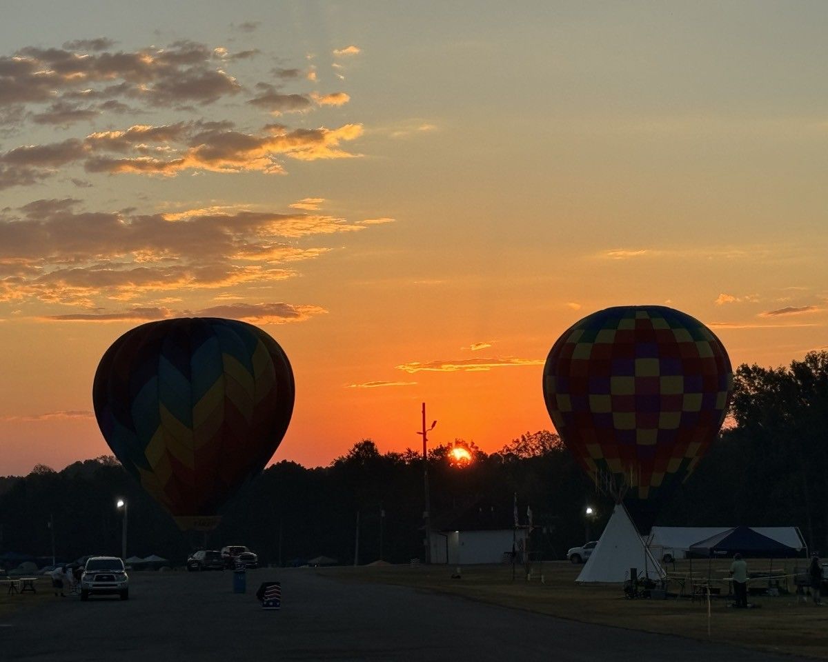 Two hot air balloons are flying in the sky at sunset.