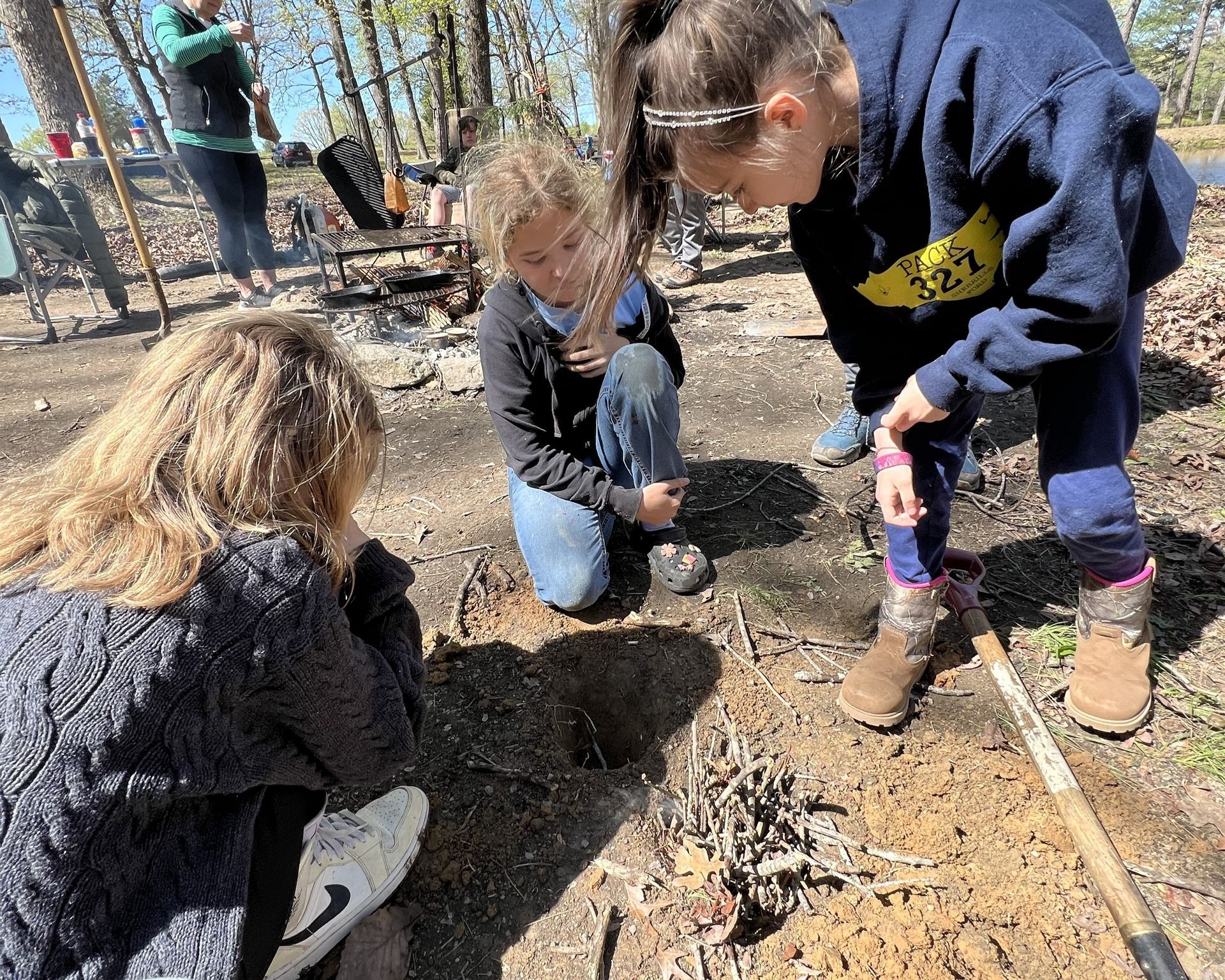 A group of children are digging in the dirt with a shovel.