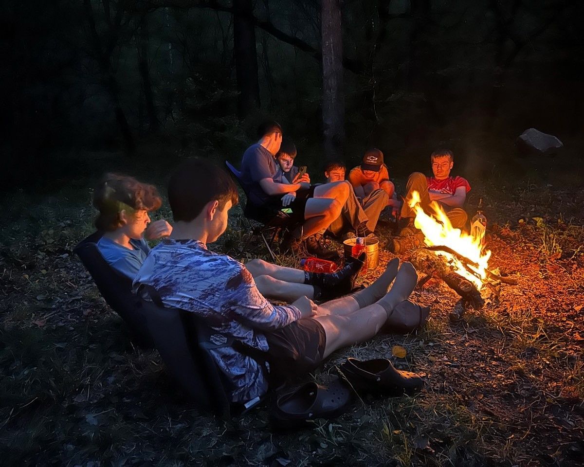People sitting around a campfire in a dark forest at night