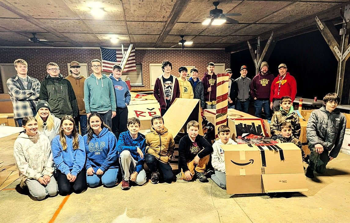 Group of people posing indoors with boxes and bags in a warehouse-like space