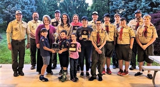A group of boy scouts and their families are posing for a picture.