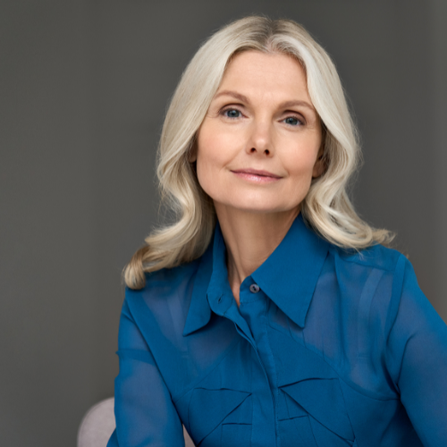 Woman with silver hair wearing a blue shirt, smiling at the camera.