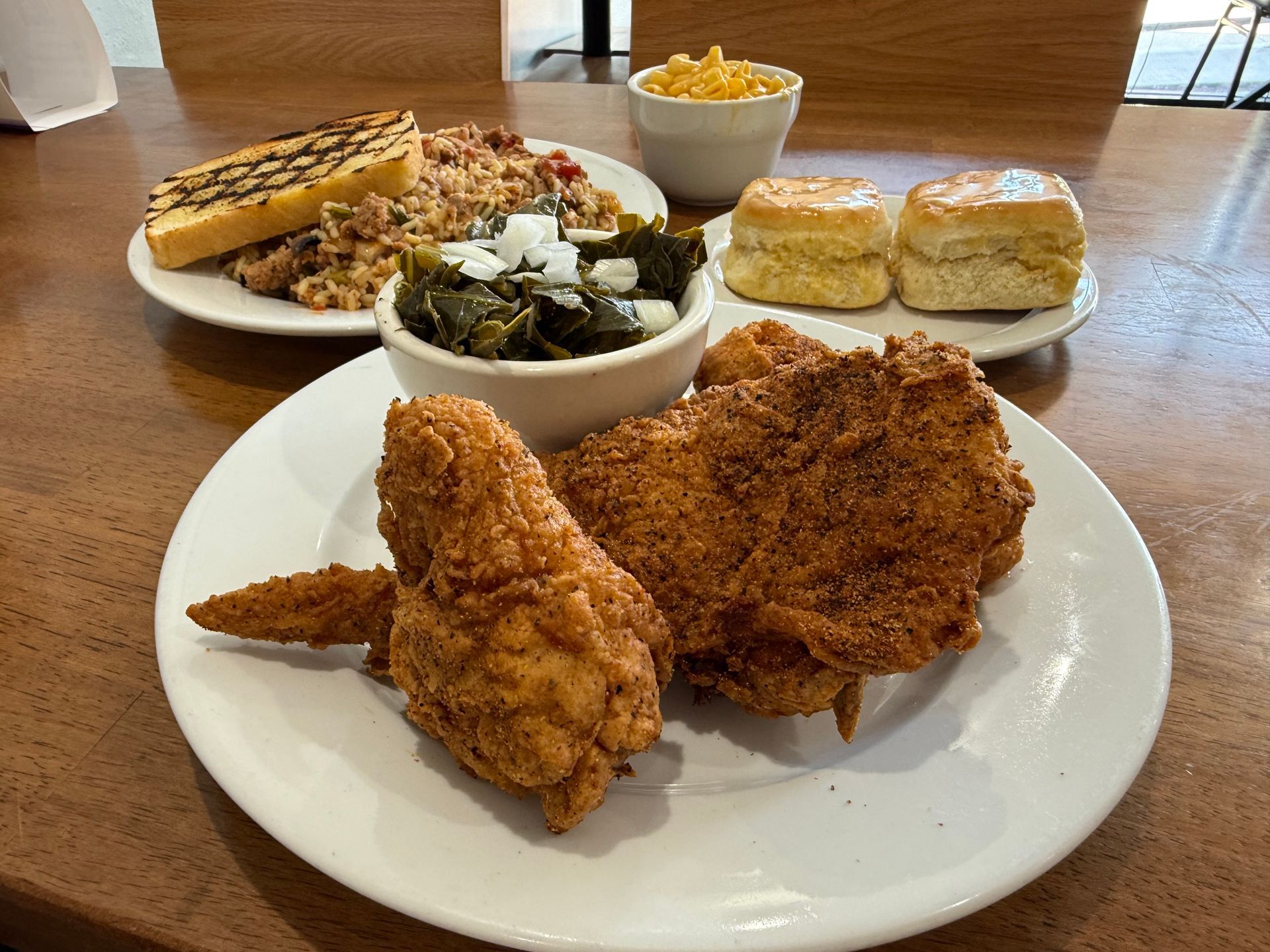 Fried chicken meal: plate of fried chicken, collard greens, cornbread, biscuits, stuffing, and mac and cheese.