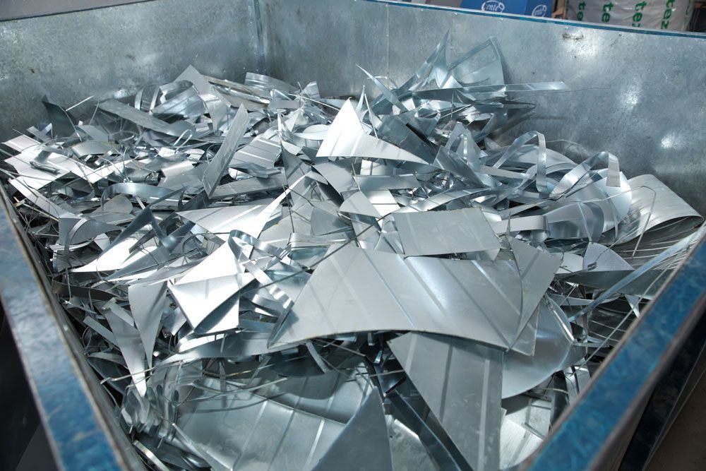 Shiny metal scraps piled in a large industrial bin