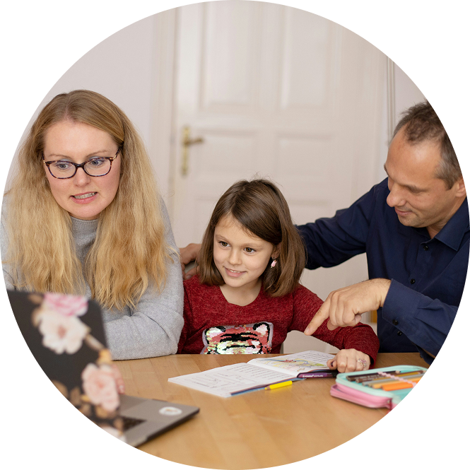 Three people at a table reviewing a workbook, with one pointing at the page.