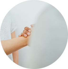 Handshake through frosted glass, showing clasped hands in a soft white setting