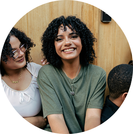 Three people smiling indoors, with a wooden wall background.