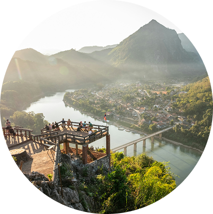Scenic mountain overlook with a river valley, town, and viewing platform at sunrise