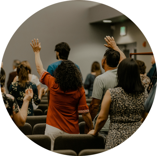 People standing and raising hands during a church or worship service in an auditorium.