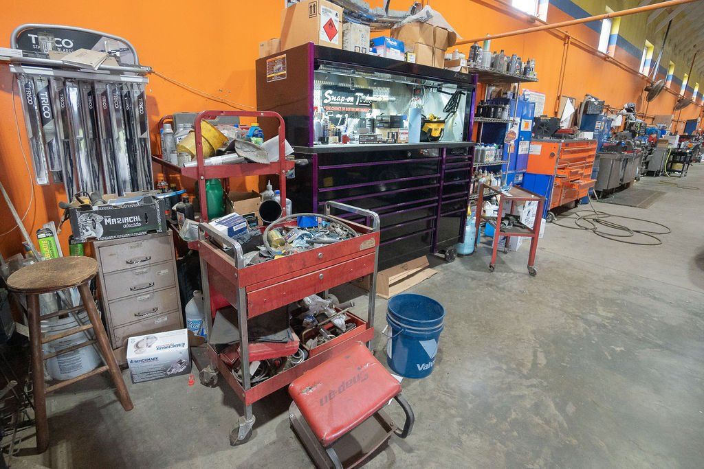 Garage interior with tools, shelves, and a workbench along an orange wall.
