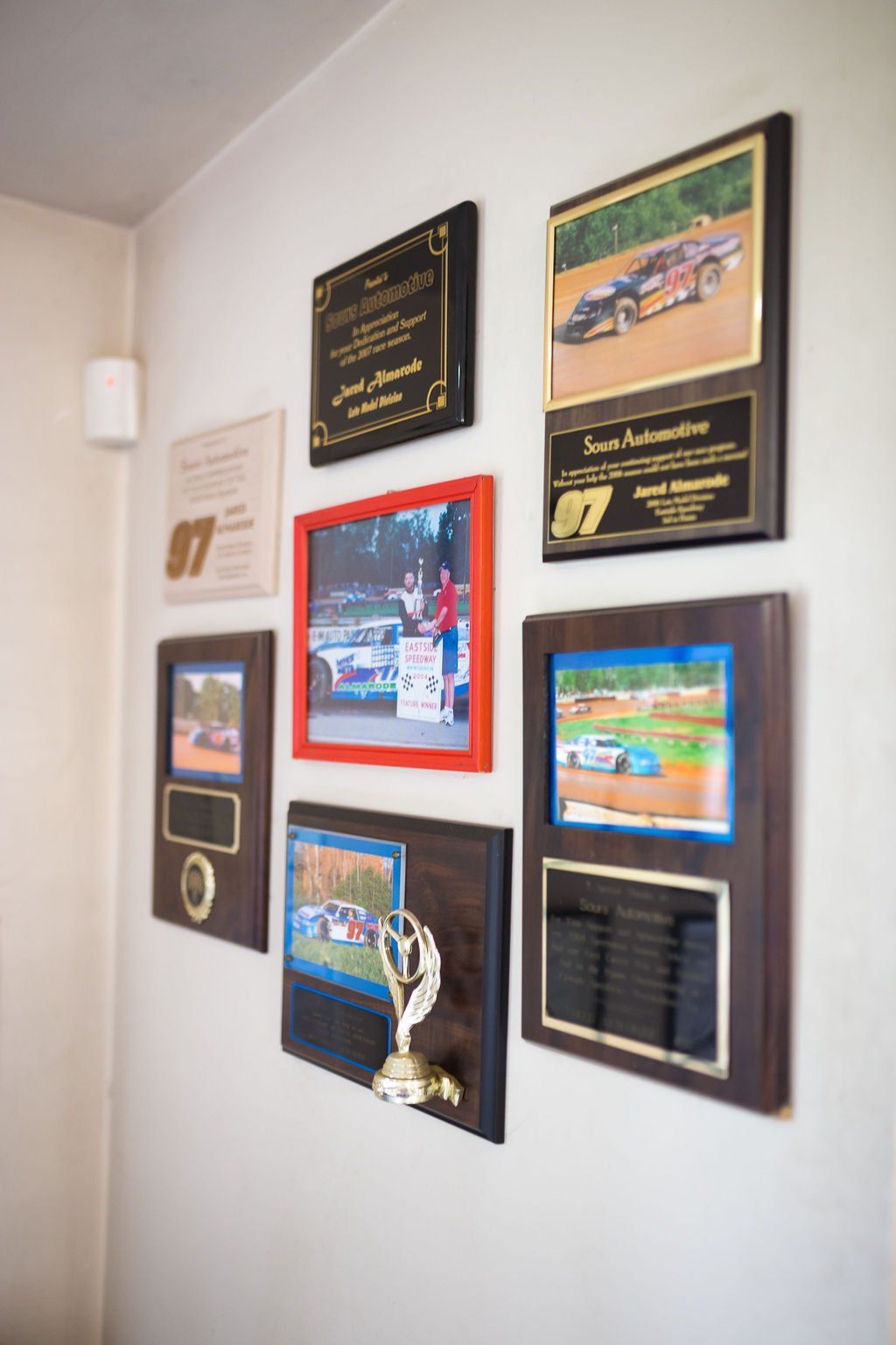 Wall with framed racing trophies and photos.