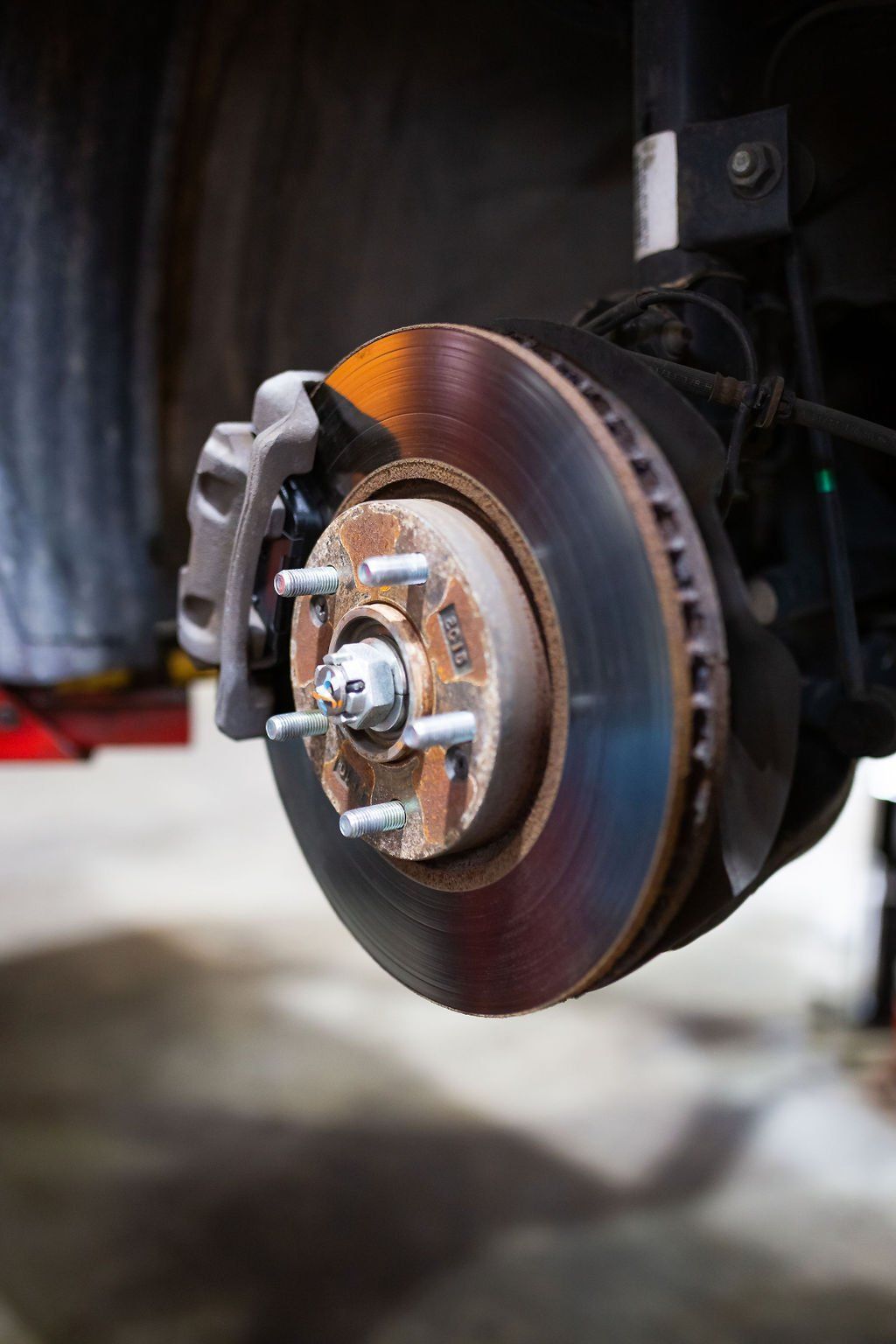 Car brake rotor and caliper assembly; rust and wear are visible.