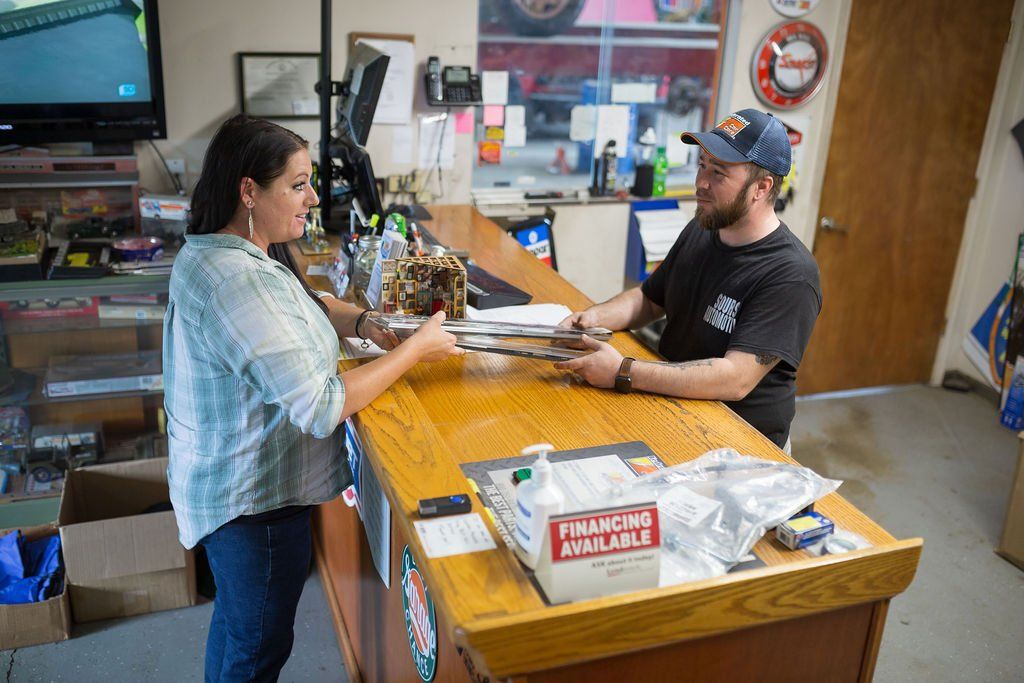 Woman and man at a counter exchanging items in an auto shop.
