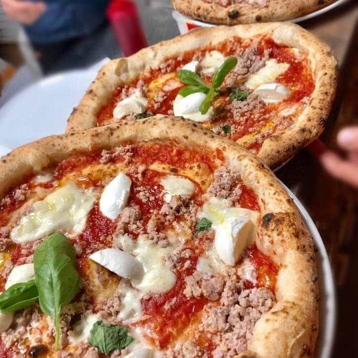 Due piccole pizze condite con salsa di pomodoro, formaggio, basilico e salsiccia su un piatto
