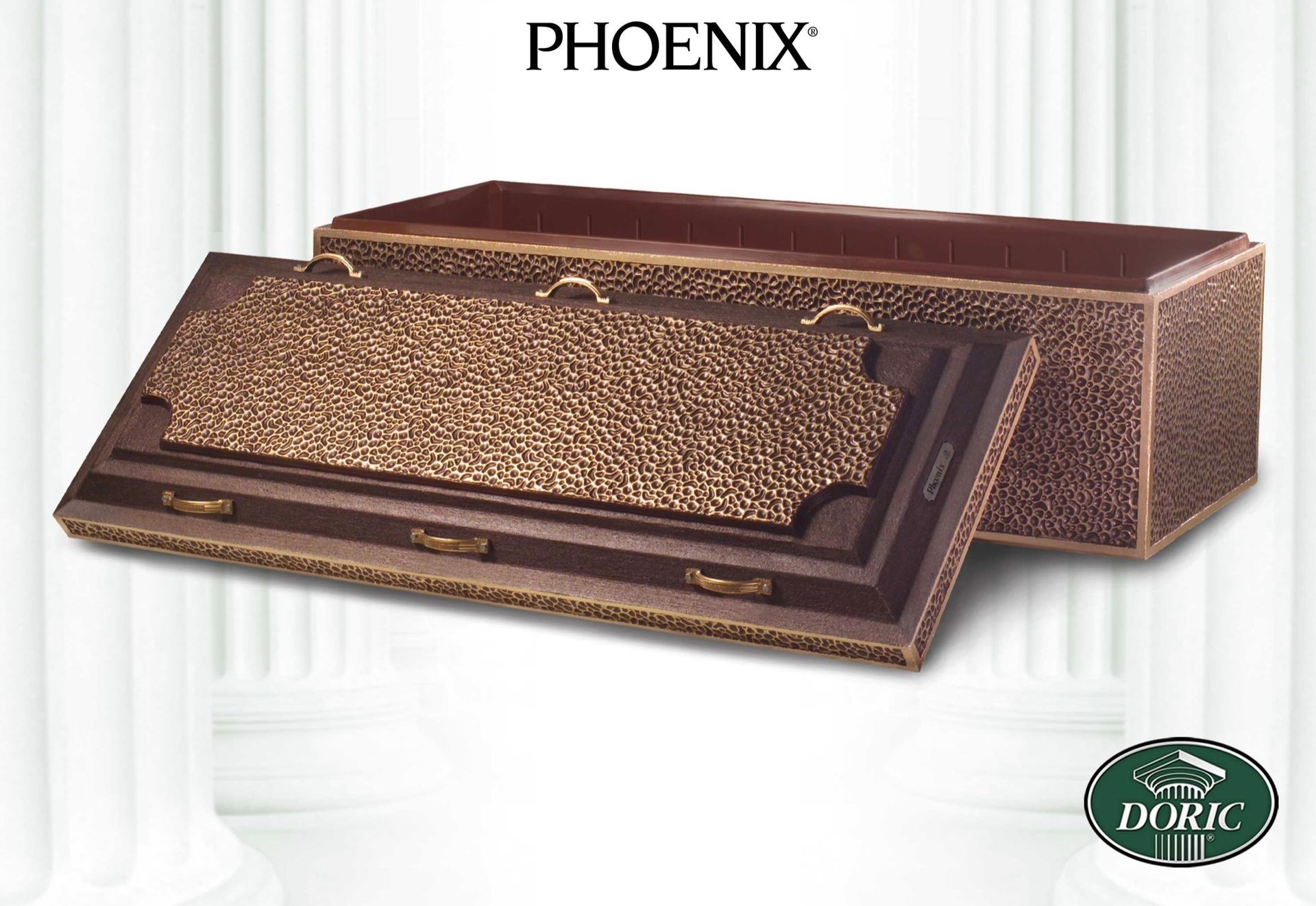 A bronze-colored Phoenix funeral casket with ornate metal handles, displayed against a backdrop of white pillars.