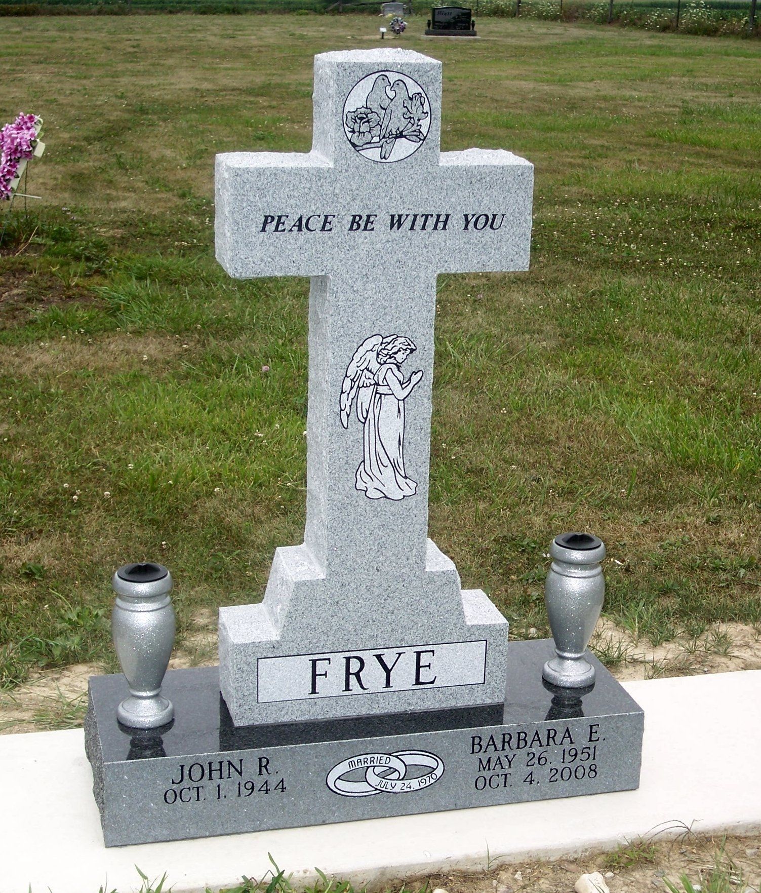 A grey granite cross-shaped tombstone inscribed with