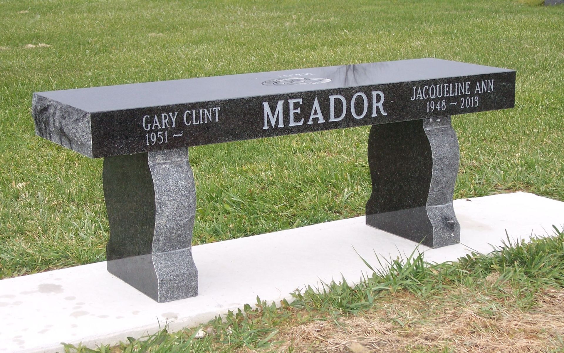 A black granite memorial bench engraved with