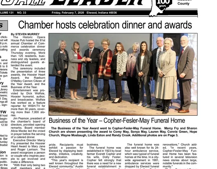 A group of people standing on a stage at a chamber of commerce dinner and awards ceremony.