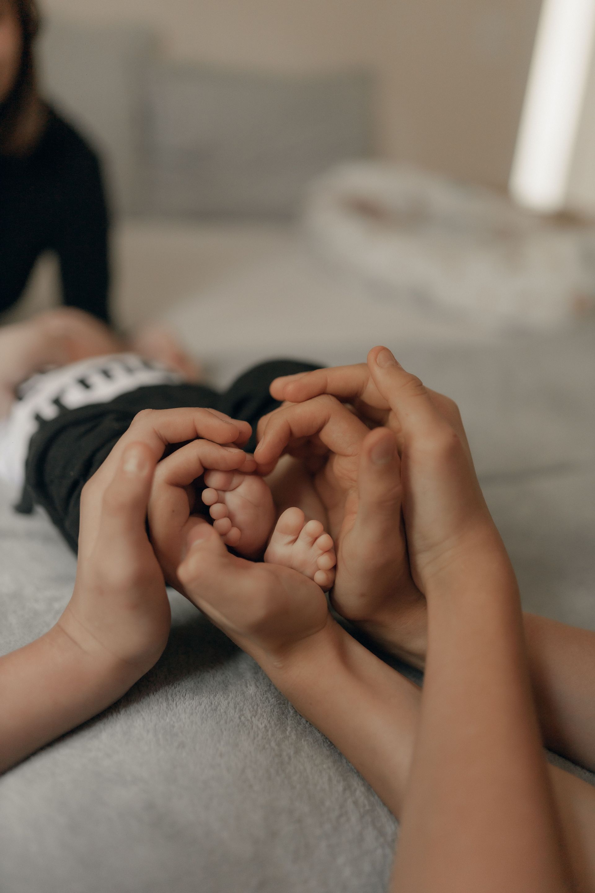 Hands and a baby's feet forming a heart on a bed