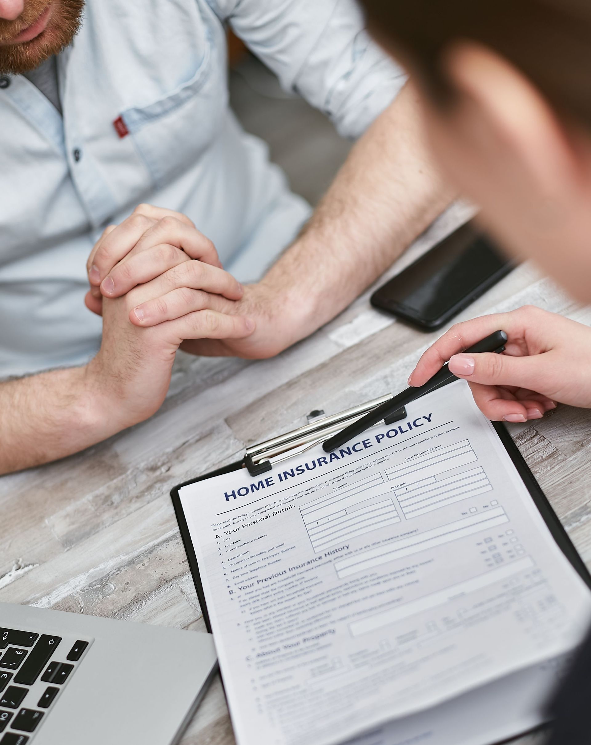 Hands reviewing a resume form at a desk with a laptop nearby