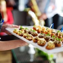 A person is holding a tray of food on a table.