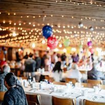 A group of people are sitting at tables in a restaurant with balloons hanging from the ceiling.
