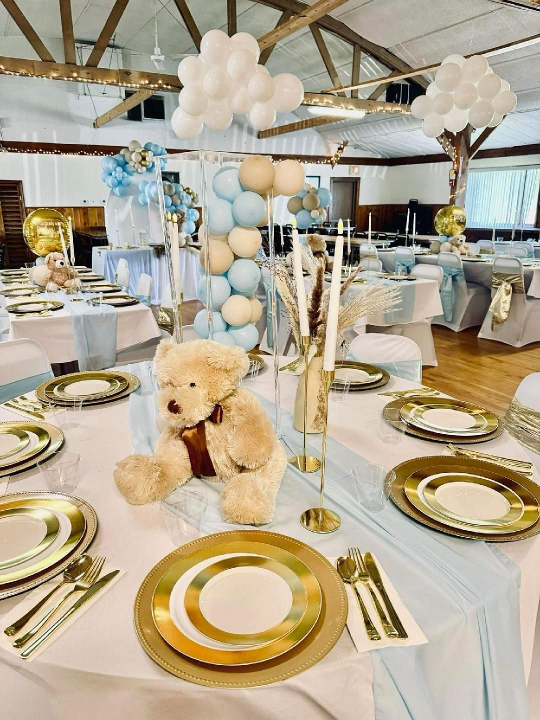 A teddy bear is sitting on top of a table decorated for a baby shower.