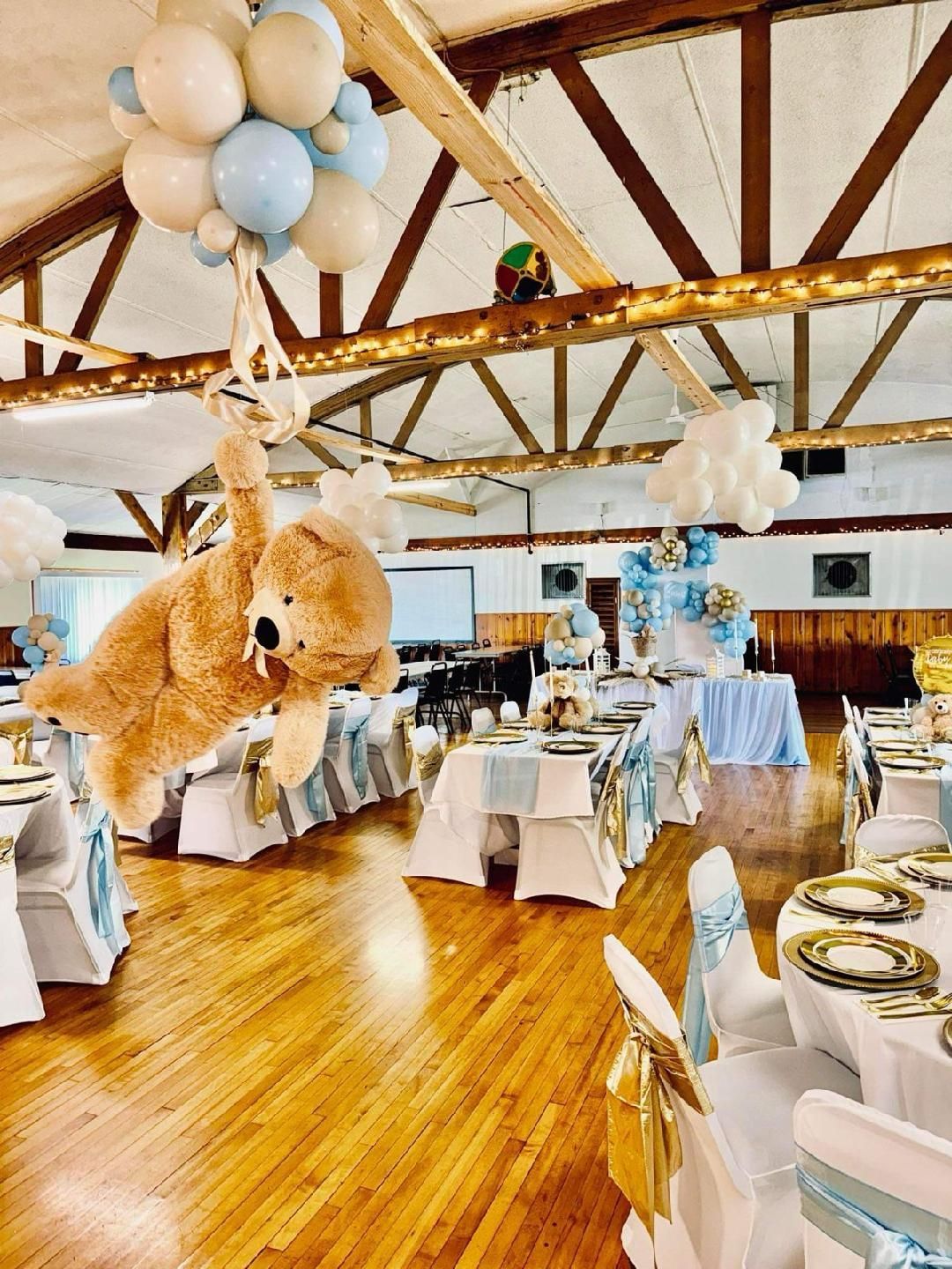 A teddy bear is hanging from the ceiling of a room decorated for a baby shower.