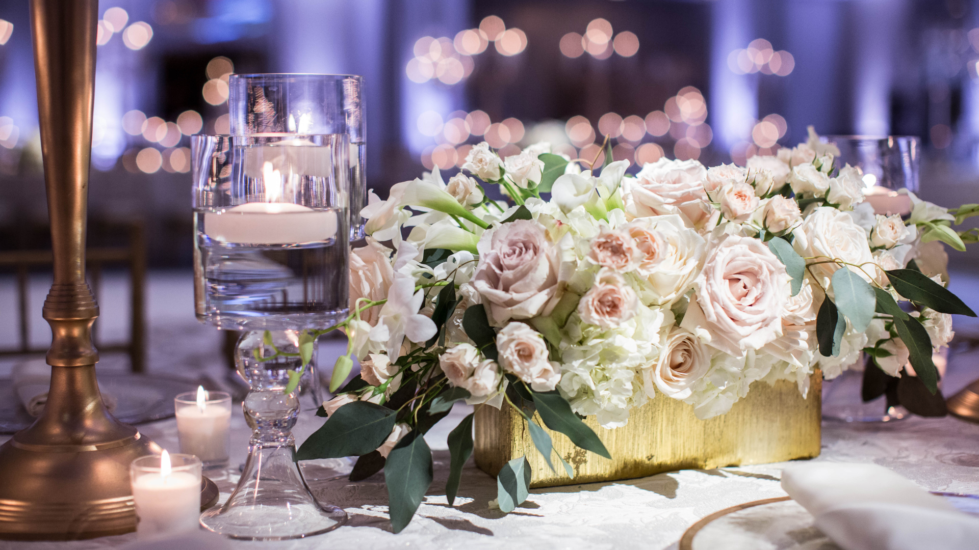 A table with a vase of flowers and candles on it