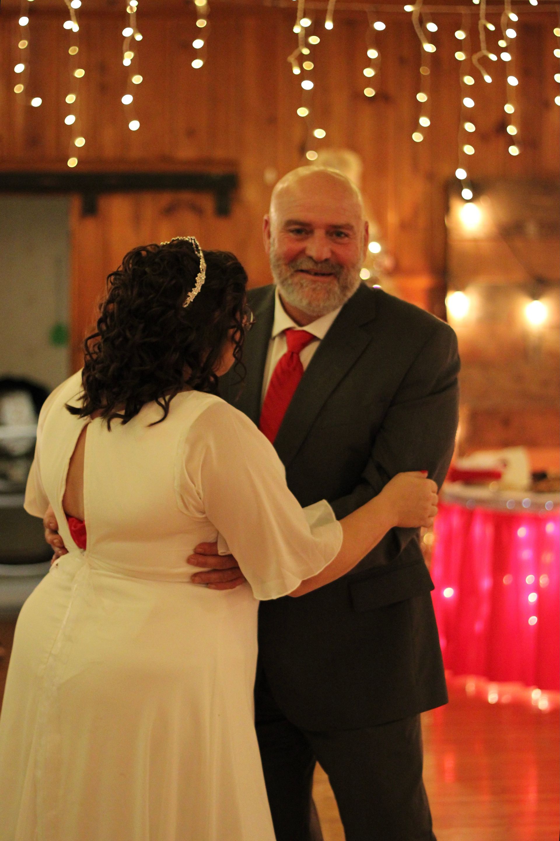 A man in a suit and tie is dancing with a woman in a white dress.