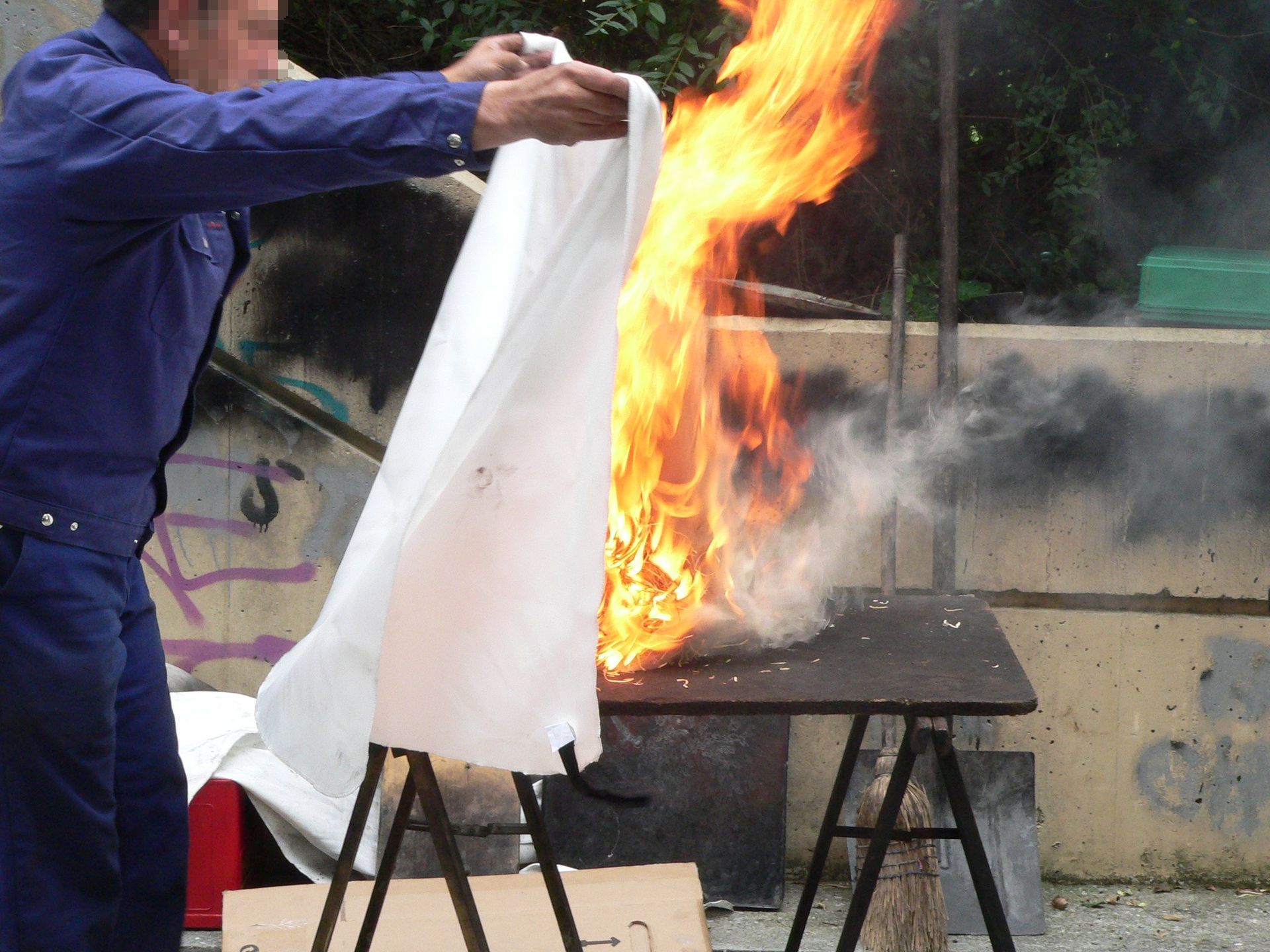A man is holding a piece of cloth in front of a fire